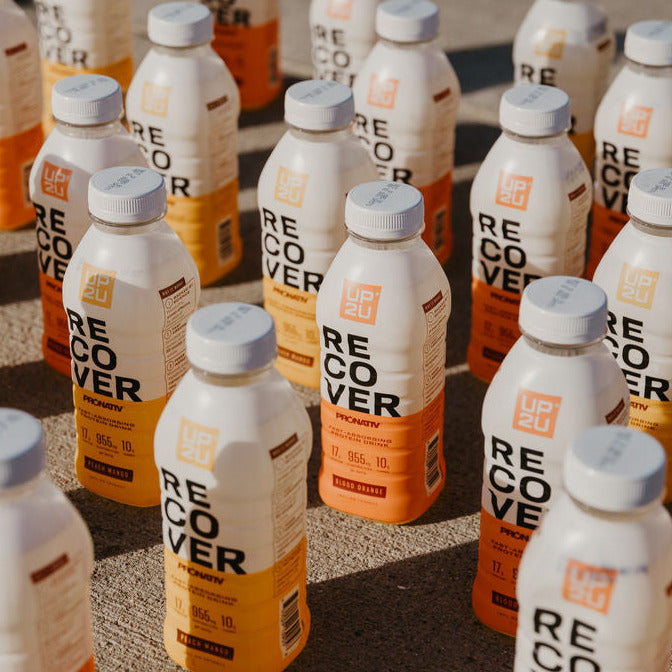Lineup of numerous bottles of UP2U recovery drink filling the screen.