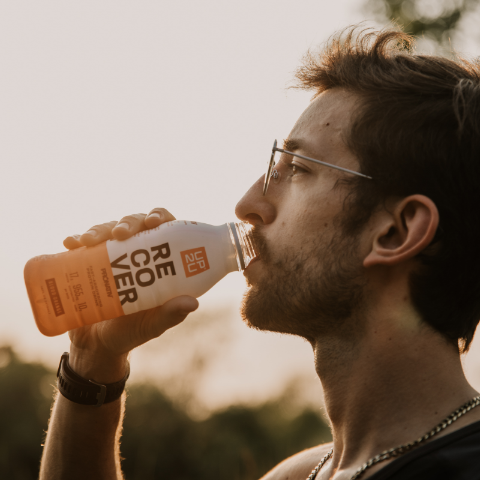 Close up of a runner taking a drink of UP2U recovery drink.